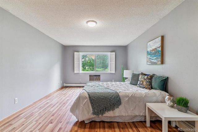 13626 E Bates Ave Unit 110, Aurora, CO 80014 - bedroom with a baseboard radiator, wood finished floors, a wall mounted air conditioner, a textured ceiling, and baseboards