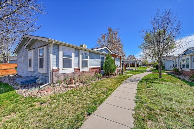 6631 E 78th Ave, Commerce City, CO 80022 - view of side of home with a lawn, a chimney, brick siding, and fence
