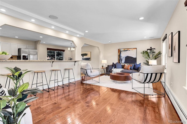 living area featuring a chandelier, hardwood / wood-style flooring, recessed lighting, baseboards, and baseboard heating