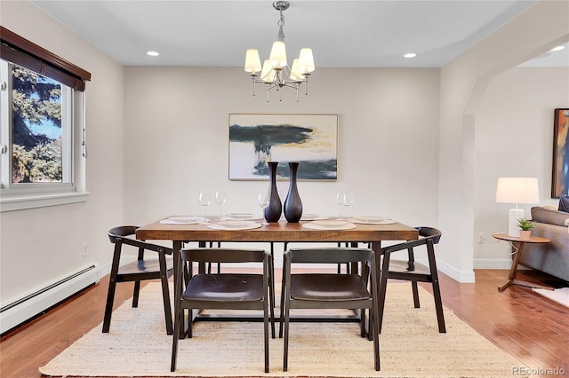 dining space featuring a baseboard heating unit, baseboards, an inviting chandelier, and wood finished floors