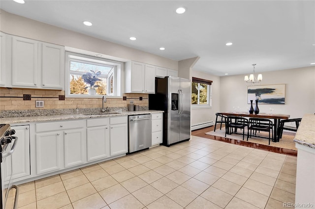 kitchen featuring light tile patterned floors, stainless steel appliances, a sink, white cabinetry, and backsplash