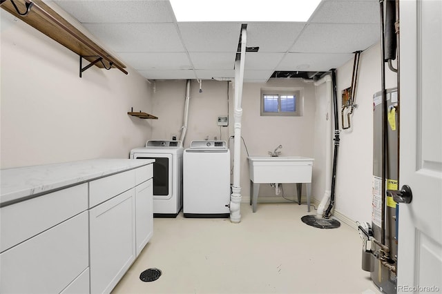 laundry area featuring cabinet space, baseboards, gas water heater, separate washer and dryer, and a sink