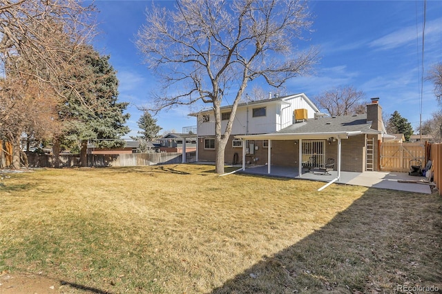 rear view of property featuring a fenced backyard, brick siding, a yard, a chimney, and a patio area