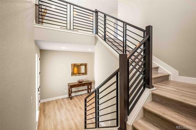 staircase with a towering ceiling and wood-type flooring