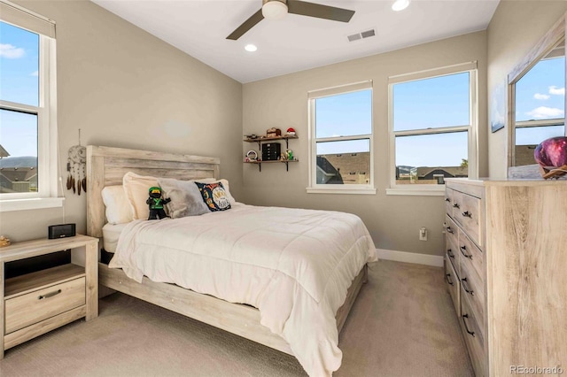 bedroom with multiple windows, ceiling fan, and light colored carpet