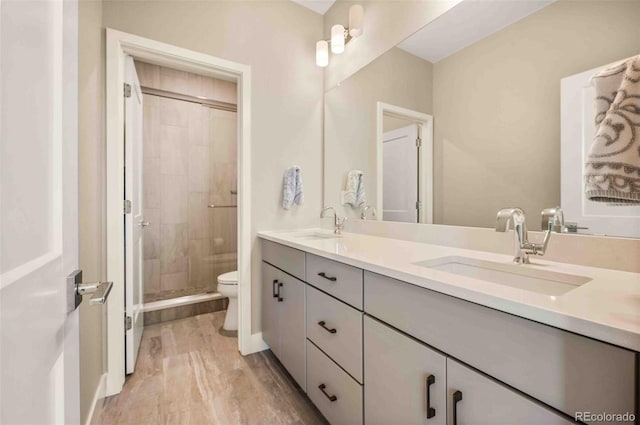 bathroom with hardwood / wood-style floors, vanity, a tile shower, and toilet