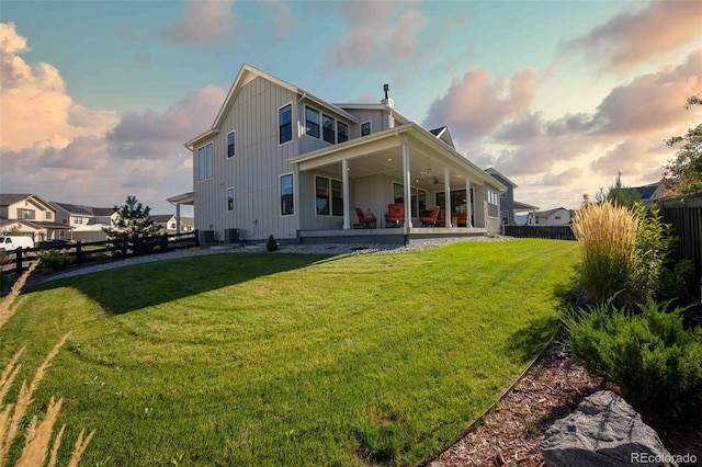 back house at dusk featuring a yard, a patio, and ceiling fan