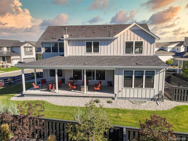 back house at dusk with outdoor lounge area, a yard, and a patio