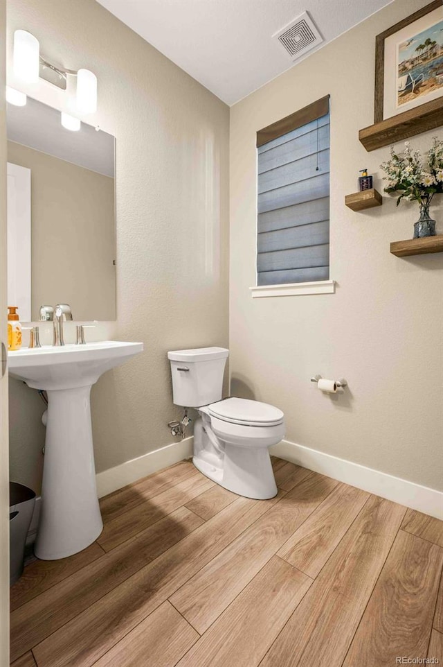 bathroom with toilet, baseboards, visible vents, and wood finished floors