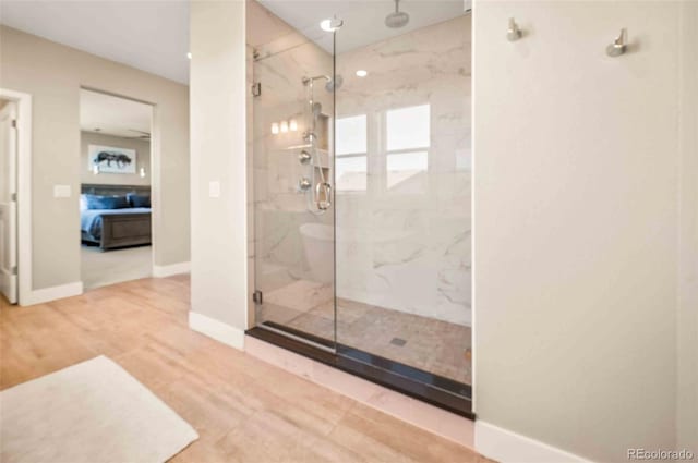 ensuite bathroom with a marble finish shower, baseboards, wood finished floors, and ensuite bathroom