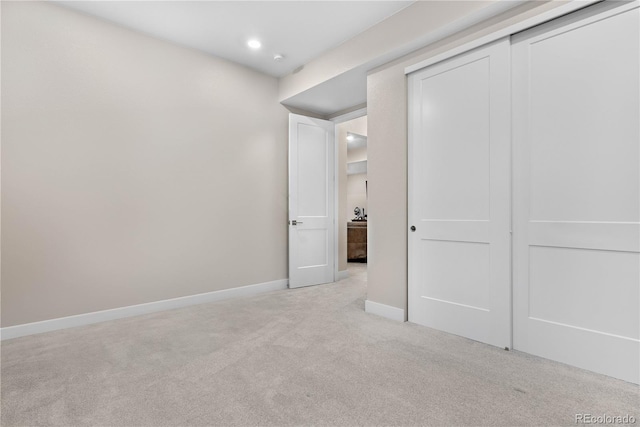 unfurnished bedroom with baseboards, a closet, and light colored carpet