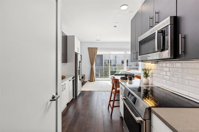 2550 Lawrence St Unit Rb306, Denver, CO 80205 - kitchen featuring appliances with stainless steel finishes, dark wood-style flooring, decorative backsplash, white cabinets, and recessed lighting