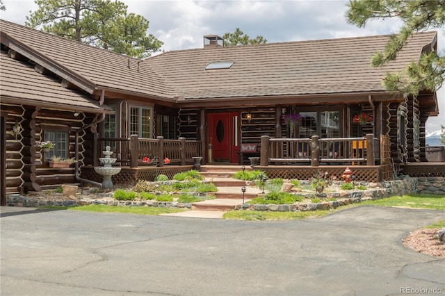 29095 Summit Ranch Dr, Golden, CO 80401 - log-style house featuring log siding, a chimney, and a porch