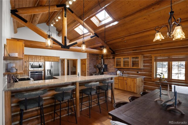 29095 Summit Ranch Dr, Golden, CO 80401 - kitchen with stainless steel appliances, a wood stove, light wood-style floors, wood ceiling with exposed beams, and a peninsula
