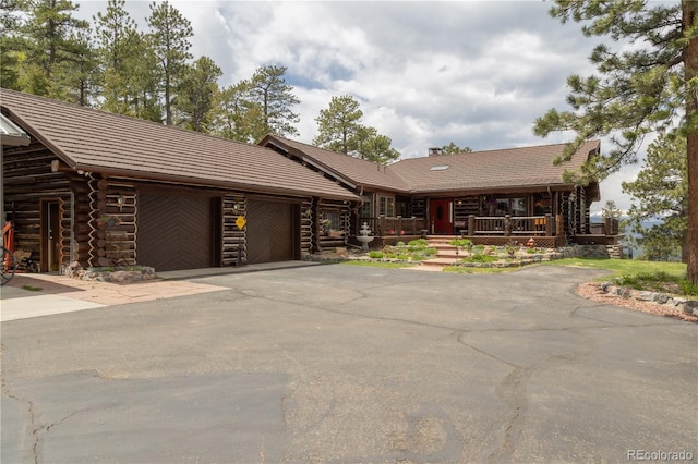 29095 Summit Ranch Dr, Golden, CO 80401 - log home featuring an attached garage, log exterior, asphalt driveway, a chimney, and covered porch