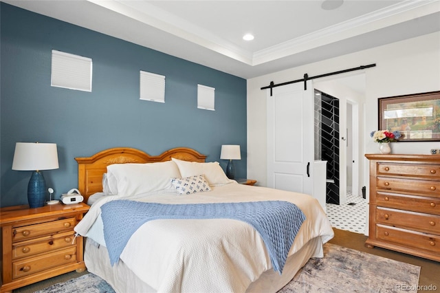 bedroom featuring ornamental molding, a barn door, and a tray ceiling