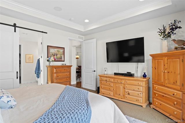 bedroom with ornamental molding, a barn door, and a raised ceiling