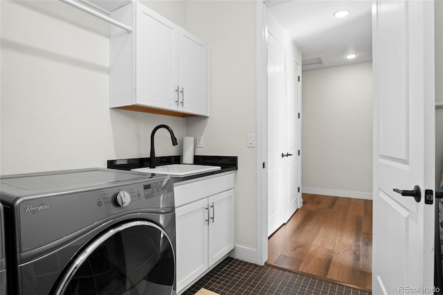 laundry area with dark hardwood / wood-style flooring, sink, washer / dryer, and cabinets