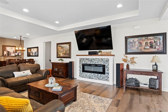 6484 Golden Briar Ln, Colorado Springs, CO 80927 - living room featuring wood finished floors, a chandelier, a tray ceiling, a tile fireplace, and recessed lighting