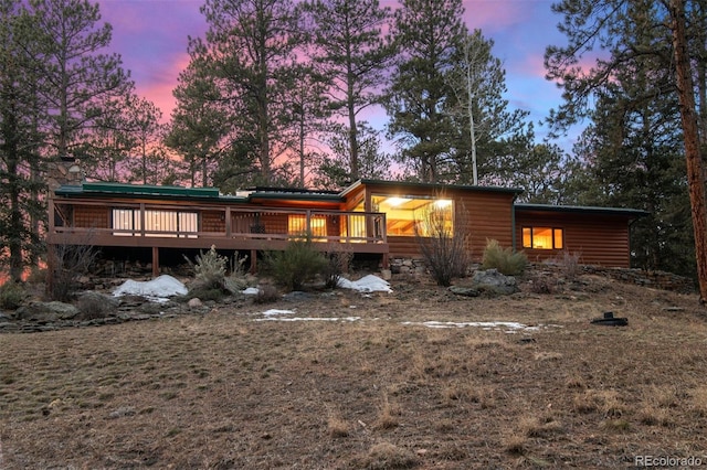 back house at dusk featuring a wooden deck