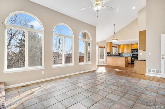 unfurnished living room featuring plenty of natural light, ceiling fan, and light tile patterned flooring