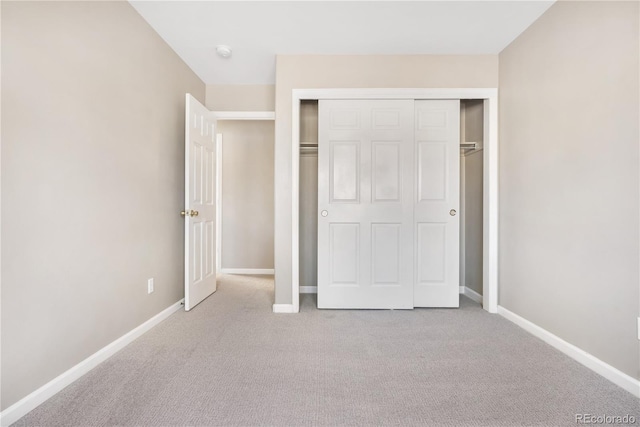 unfurnished bedroom featuring light carpet and a closet