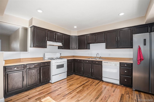 kitchen featuring light wood-style flooring, under cabinet range hood, white appliances, a sink, and light countertops