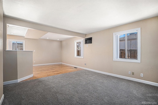 spare room featuring carpet floors, a healthy amount of sunlight, visible vents, and baseboards