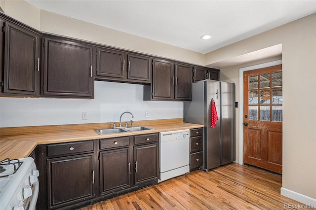 kitchen with white appliances, light wood-style flooring, light countertops, and a sink