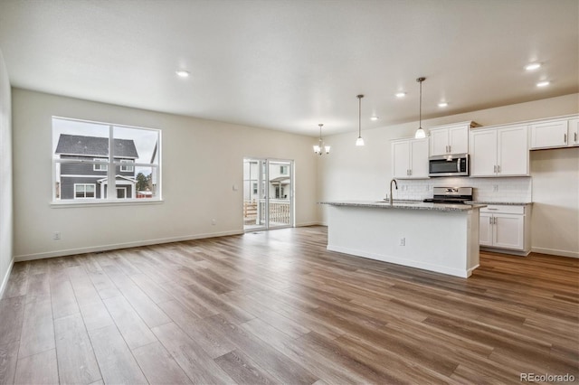 kitchen featuring pendant lighting, white cabinetry, stainless steel appliances, and an island with sink