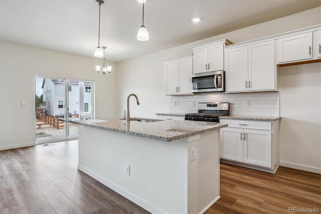 kitchen with hanging light fixtures, appliances with stainless steel finishes, sink, and white cabinets