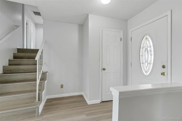 1005 S Lewiston Way, Aurora, CO 80017 - entryway with light wood finished floors, baseboards, stairway, and a textured ceiling