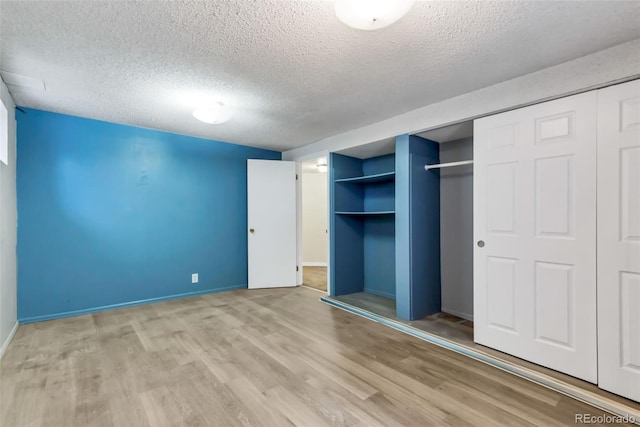 1005 S Lewiston Way, Aurora, CO 80017 - unfurnished bedroom featuring a textured ceiling, wood finished floors, a closet, and baseboards