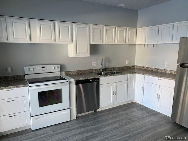 kitchen with dark wood-type flooring, appliances with stainless steel finishes, sink, and white cabinets