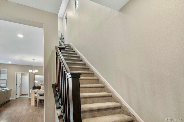 stairs featuring a notable chandelier and hardwood / wood-style flooring