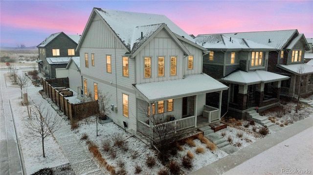 snow covered rear of property featuring a porch