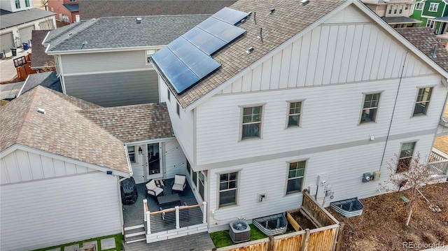 rear view of property featuring an outdoor hangout area, cooling unit, and solar panels