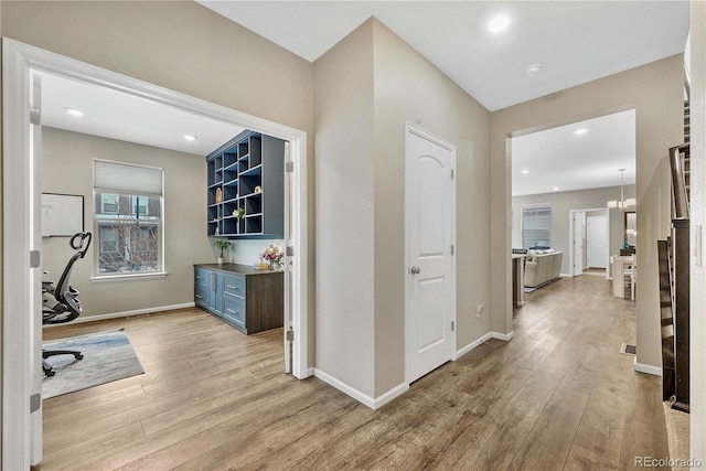 home office with an inviting chandelier and light hardwood / wood-style flooring