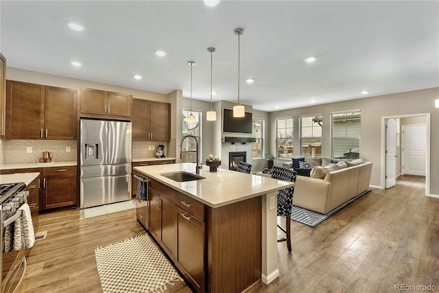 kitchen with appliances with stainless steel finishes, decorative light fixtures, sink, a kitchen breakfast bar, and a kitchen island with sink