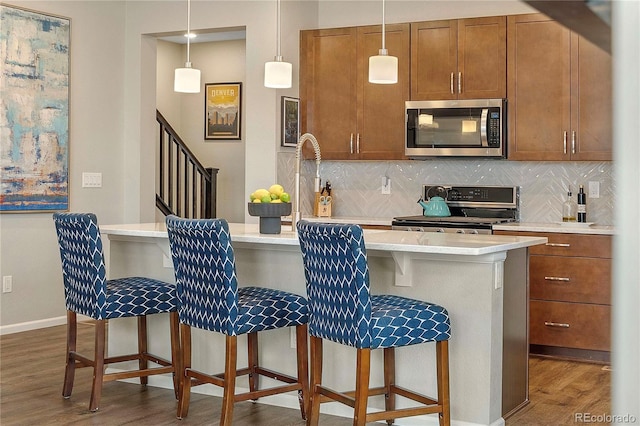 kitchen with stainless steel appliances, a breakfast bar area, dark hardwood / wood-style flooring, and decorative light fixtures