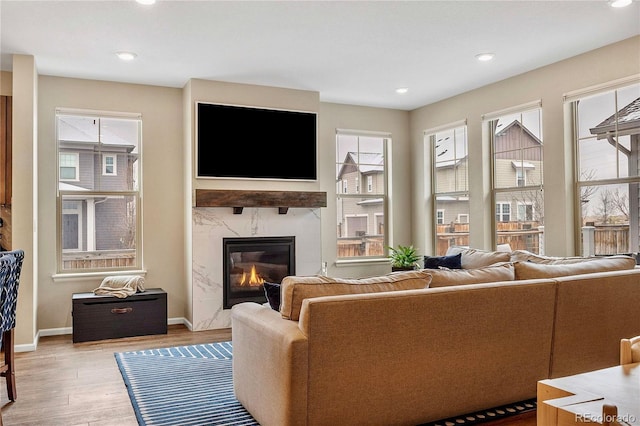 living room with a high end fireplace and light hardwood / wood-style flooring