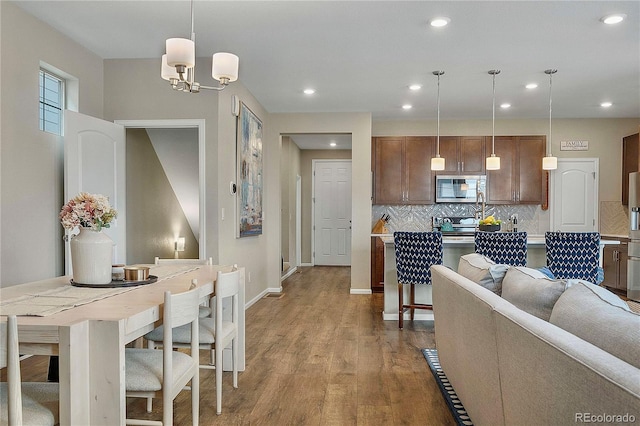 interior space featuring decorative backsplash, hanging light fixtures, and light hardwood / wood-style flooring