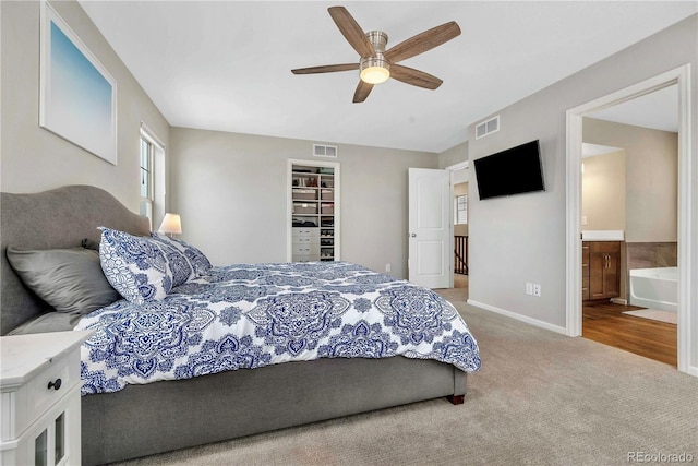 carpeted bedroom featuring ceiling fan, a spacious closet, a closet, and ensuite bath