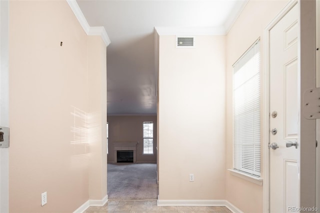 foyer featuring visible vents, baseboards, a fireplace, crown molding, and light colored carpet