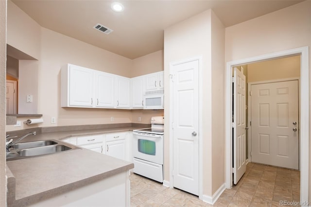 kitchen with white appliances, visible vents, a sink, light countertops, and white cabinetry