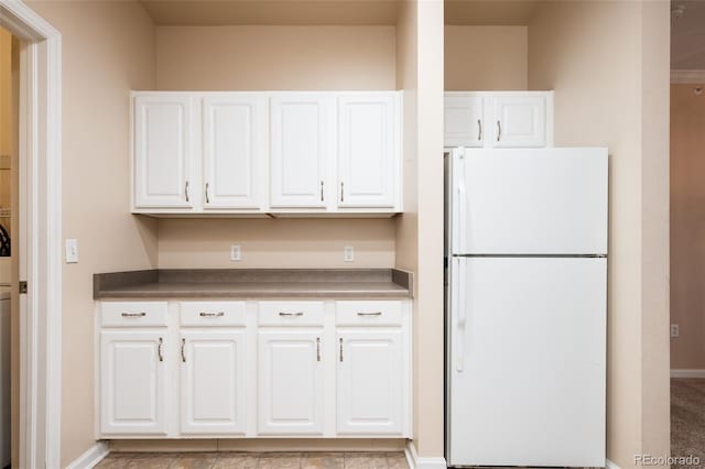 kitchen with white cabinets, freestanding refrigerator, and baseboards