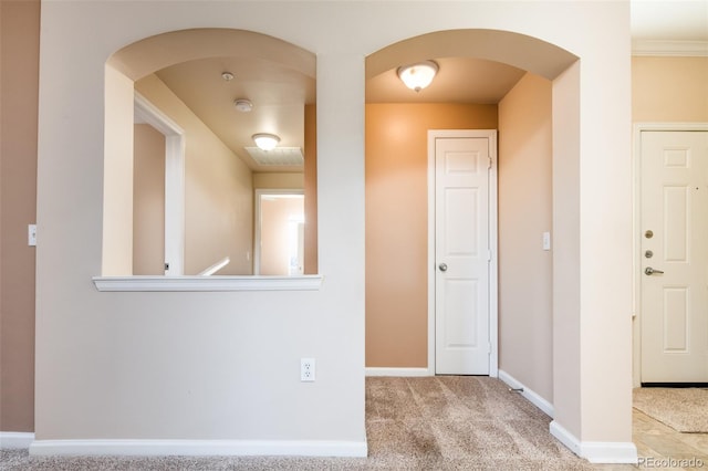 hall with baseboards, carpet floors, and arched walkways