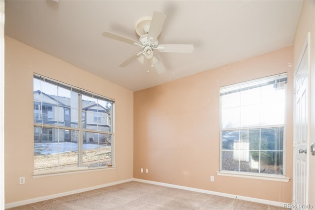 carpeted spare room featuring ceiling fan and baseboards