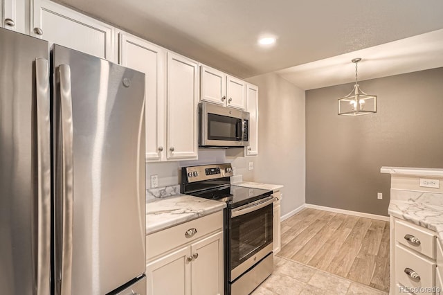 kitchen with appliances with stainless steel finishes, white cabinets, hanging light fixtures, and an inviting chandelier