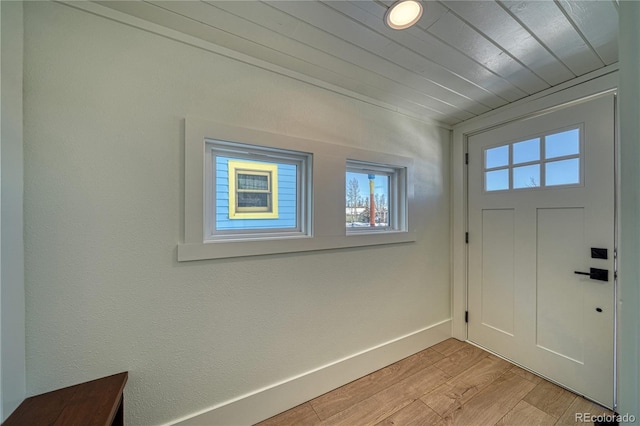 foyer entrance featuring baseboards, light wood-style floors, and wood ceiling